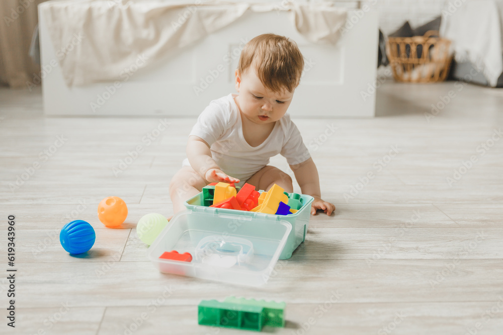 baby 6-9 months old playing with a colorful rainbow toy pyramid sitting in a white sunny bedroom. Toys for small children. Children's interior. A child with an educational toy. baby 6-9 months old playing with a colorful rainbow toy pyramid sitting in a white sunny bedroom. Toys for small children. Children's interior. A child with an educational toy.