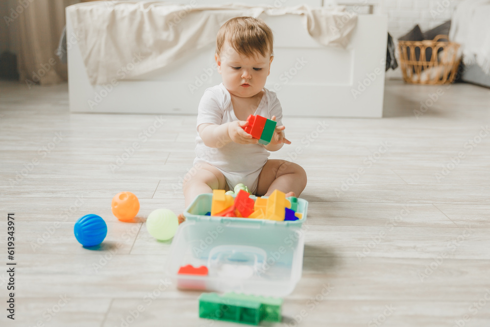 baby 6-9 months old playing with a colorful rainbow toy pyramid sitting in a white sunny bedroom. Toys for small children. Children's interior. A child with an educational toy. baby 6-9 months old playing with a colorful rainbow toy pyramid sitting in a white sunny bedroom. Toys for small children. Children's interior. A child with an educational toy.