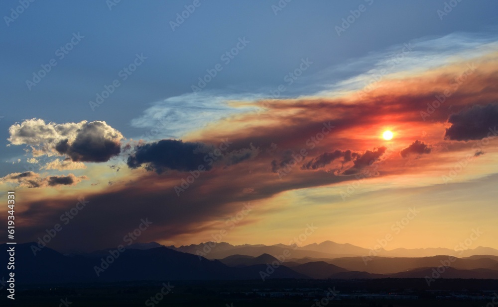 colorful sunset over the front range of the rocky mountains through the smoky haze of the spring creek wildfires near parachute, as seen from broomfield, colorado