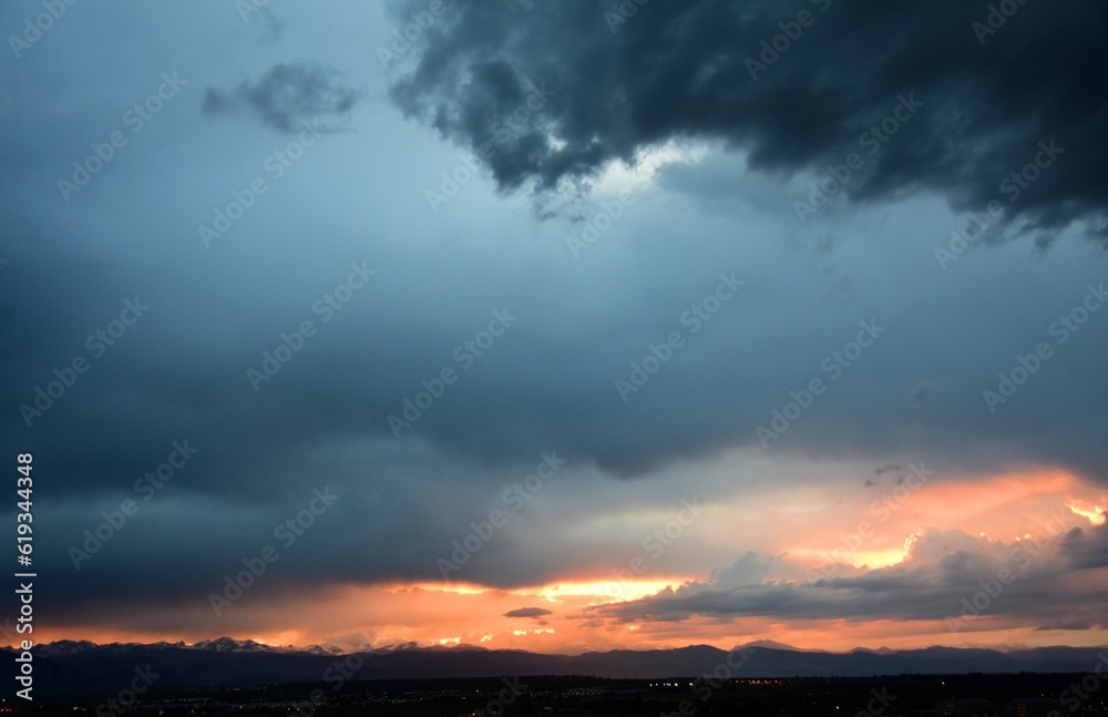 colorful sunset and storm clouds  over the front range of the rocky mountains through the smoky haze of the spring creek wildfires near parachute, as seen from broomfield, colorado