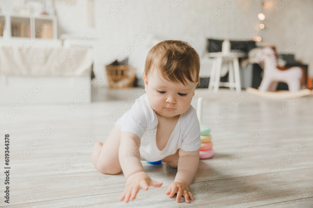 baby 6-9 months old playing with a colorful rainbow toy pyramid sitting in a white sunny bedroom. Toys for small children. Children's interior. A child with an educational toy. baby 6-9 months old playing with a colorful rainbow toy pyramid sitting in a white sunny bedroom. Toys for small children. Children's interior. A child with an educational toy.