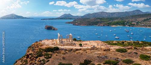 Panoramic view of the Temple of Poseidon at Cape Sounion at the edge of Attica, Greece, with moored sailboats in the bay during summer time photo