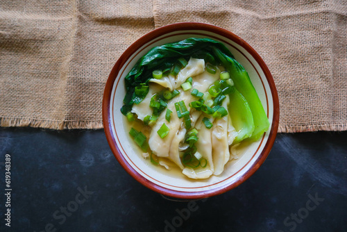 wonton soup or pangsit or dumplings soup and vegetable. wonton is traditional Chinese food of minced meat wrapped in flour sheets