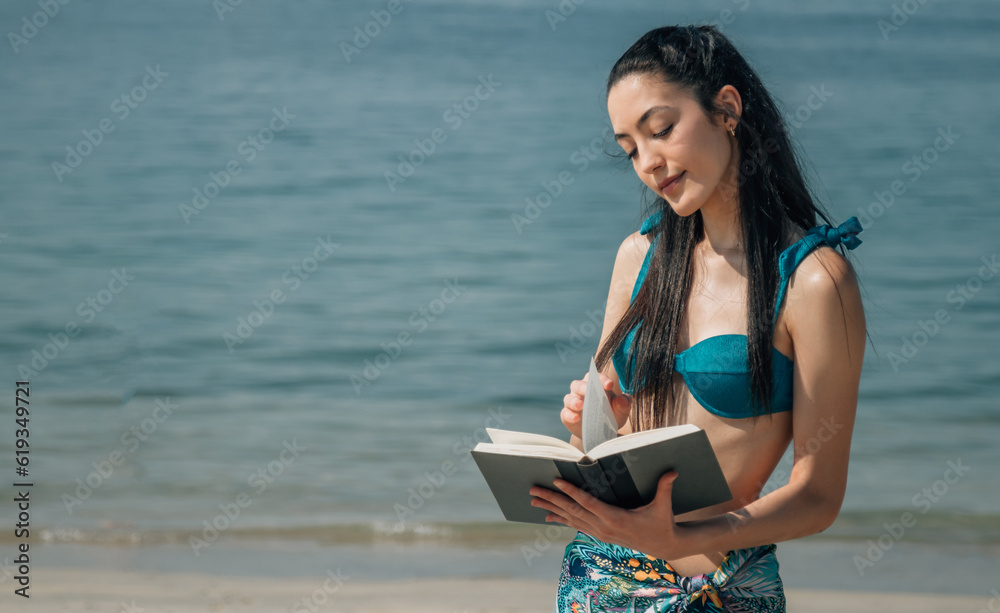 smiling woman on the beach shore reading a book
