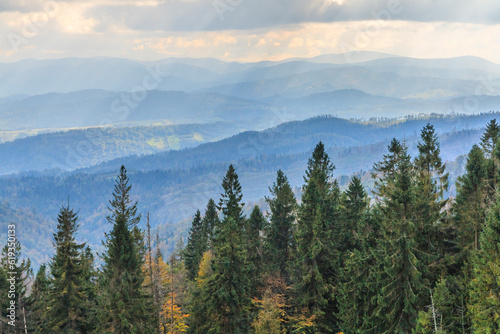 Autumn view of the peaks of Beskid Żywiecki from the tourist trail to Magurka Radziechowska near Żywiec (Poland) with a cloudy sky with streaks of sun