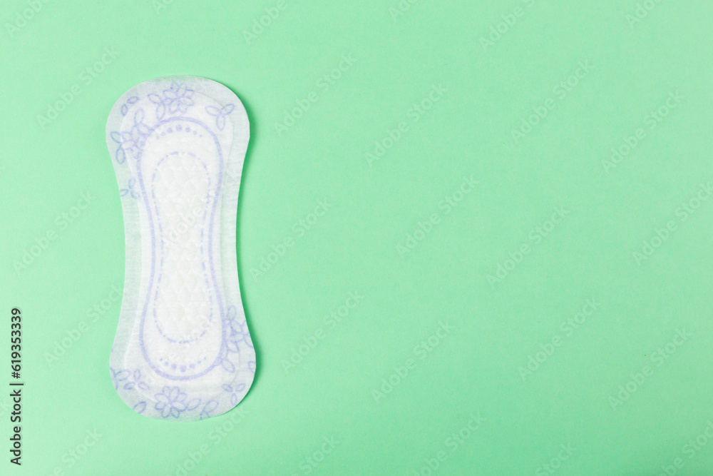 Panty liner on pastel green background. Womens hygiene