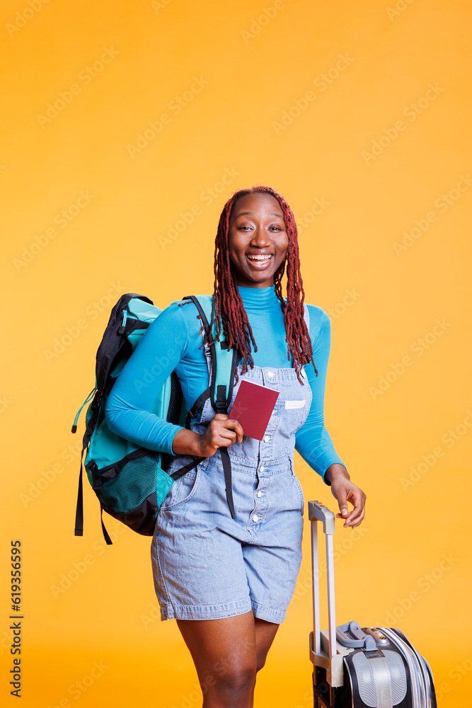 Smiling girl with id pass and luggage, travelling on international getaway with passport identification. Young adult feeling excited on vacation trip, weekend activity with suitcase.
