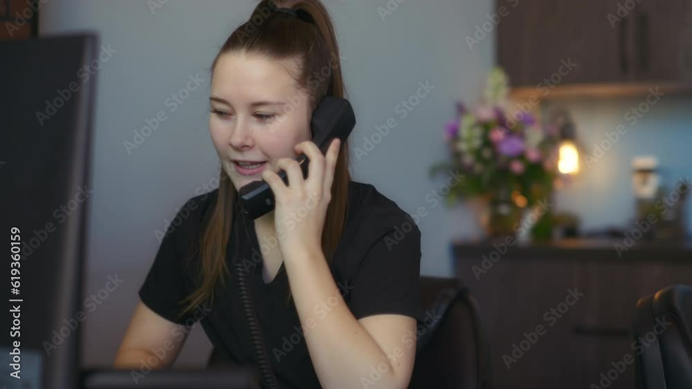Vet nurse answering the phone in the clinic reception office. Slow motion. 