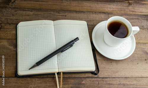 Coffee in a cup, notepad and pen on the table.