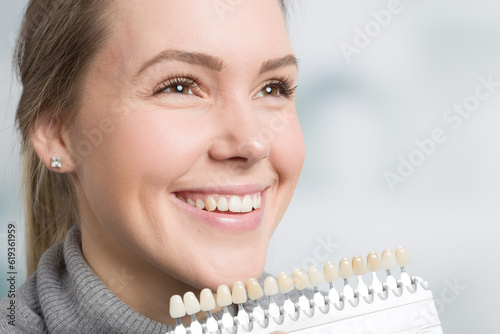 Close up of dentist using shade guide at woman's mouth to check veneer of teeth for bleaching 