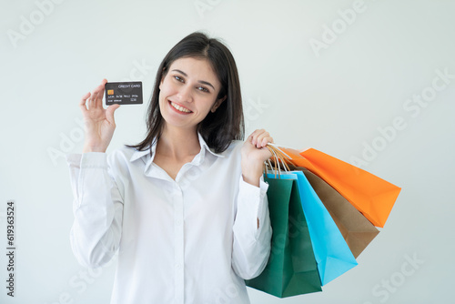 Happy beautiful woman showing credit card and shopping bags with goods, buying with discounts.
