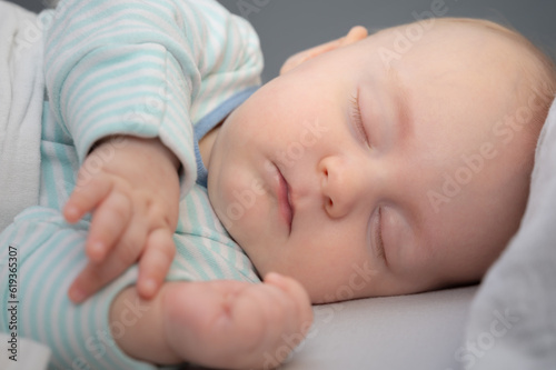 Carefree sleep little baby boy in his bed in room. Peaceful child lying on bed with closed eyes. Closeup portrait.