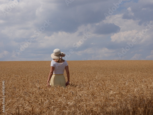 woman with hat in corn field with sun and clouds