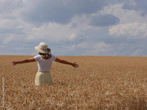 woman with hat in corn field with sun and clouds