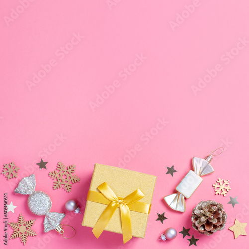 Christmas pink border with golden gift box with mini Christmas trees and shiny baubles on pastel pink background, Christmas border, copy space. Christmas gift idea, holiday presents concept