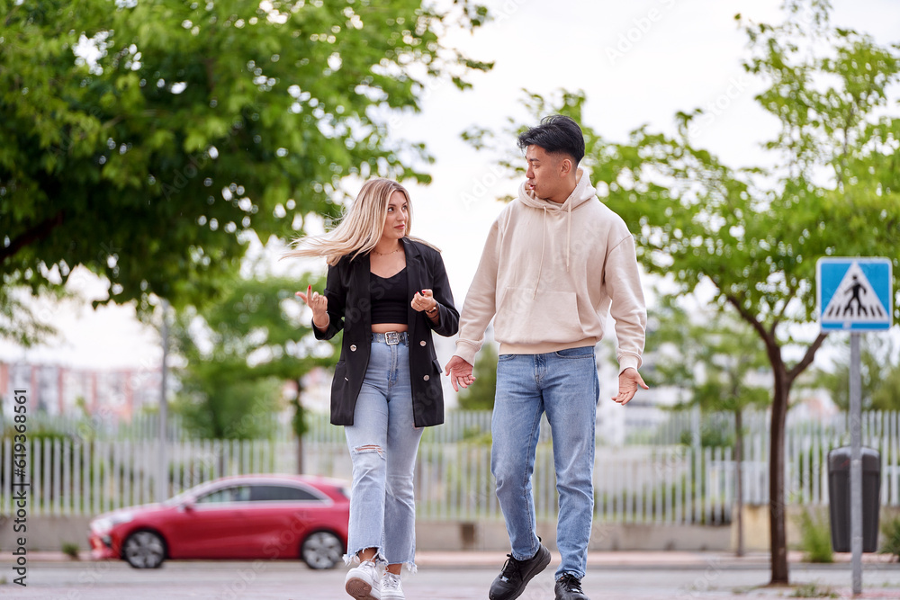 Fototapeta premium Man and woman talking while walking outdoors on the street.
