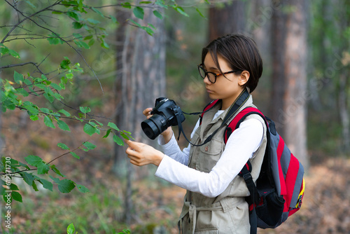 Girl naturalist taking a photo in the forest.