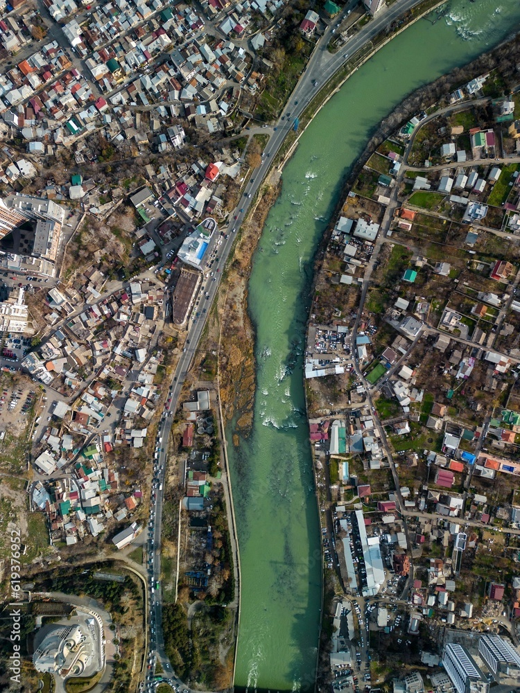 Fototapeta premium Aerial view of Tbilisi cityscape houses and a bridge on a river in Georgia