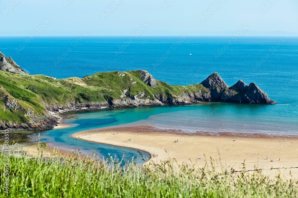 Vast expanse of serene blue-green water with coastal cliffs. Three Cliffs Bay, UK.