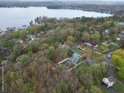 Aerial view of lake Attitash and a town near a shoreline surrounded by colorful trees in autumn photo