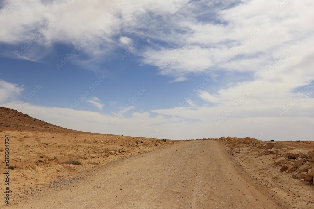 Scenic view of a desert dirt road at the foot of a hill