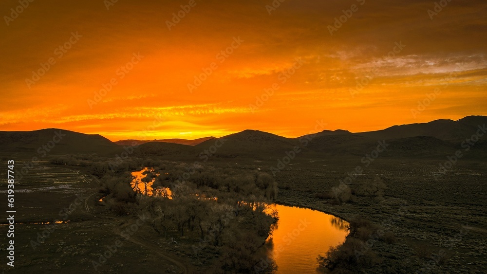 Magnificent sunrise illuminating the rolling hills and a meandering stream in the foreground