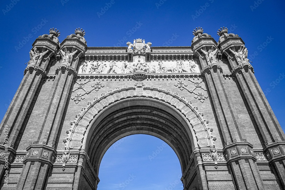 Low angle shot of the historic Arc de Triomphe against a blue sky in Barcelona, Spain