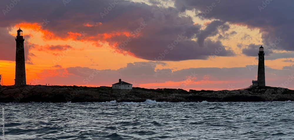 Aerial view of sea waves in background of stony lighthouses during sunset