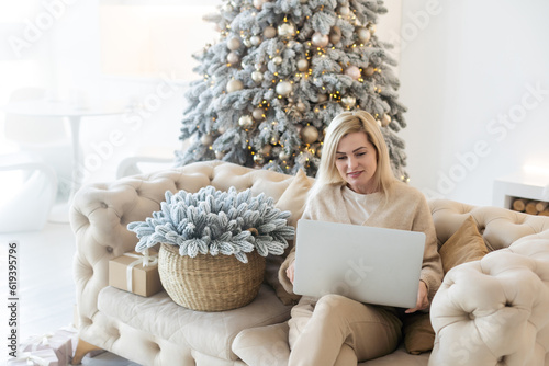 Excited smiling woman have laptop video chat. Young female at home in happy Christmas mood. photo