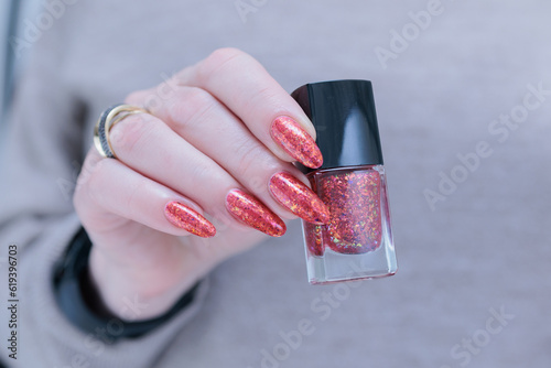 Female beautiful hand with long nails and a bright red orange nail polish photo