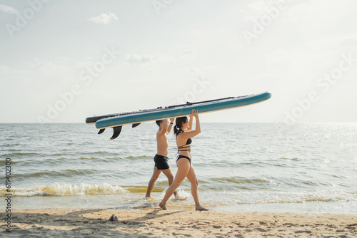 Young people surf an active lifestyle, go for a ride on the sup board.  Summer lake friends go on vacation on the weekend. Dressed in bathing clothes.