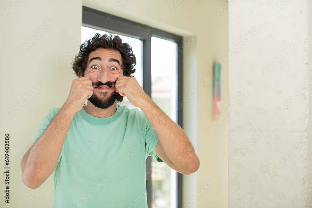 young crazy bearded man smiling and pointing to own fake smile young crazy bearded man smiling and pointing to own fake smile