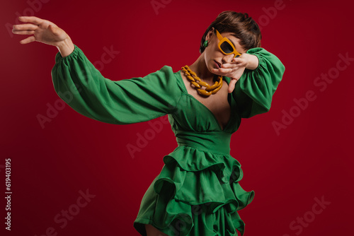 Attractive young short hair woman in elegant dress dancing against red background