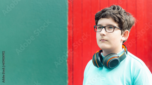 Portrait of eleven years old boy in glasses and wireless headphones, horizontal, copy space photo