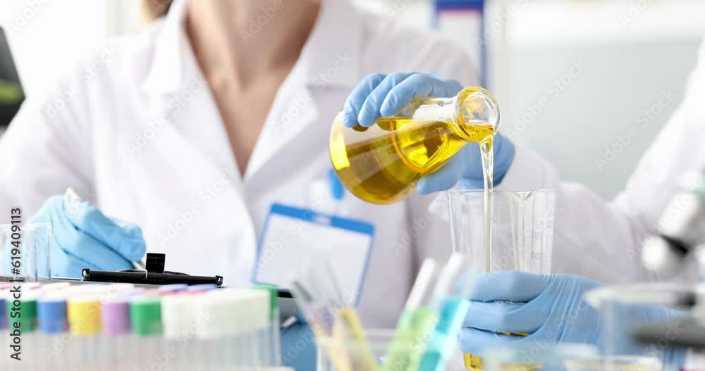 Chemist pouring oil into glass from flask 4k movie. Engine oil quality control concept Chemist pouring oil into glass from flask 4k movie. Engine oil quality control concept