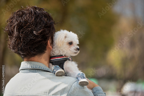 ペットの犬を肩に乗せて公園を歩く男性の後ろ姿 photo