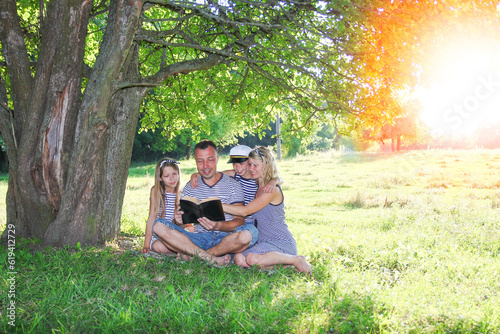 family reading bible in nature © Kostia