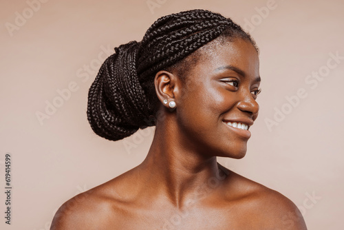 Beautiful black girl. Beauty portrait of african woman with clean healthy skin over beige background. Smiling beautiful female with black braid hair, top knot hairstyle.