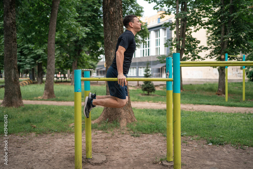 Middle age adult man doing outdoors workout on bars in park, healthy active lifestyle 