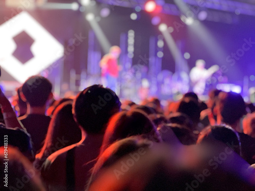 Rear view of crowded people in the concert with blurred stage in background