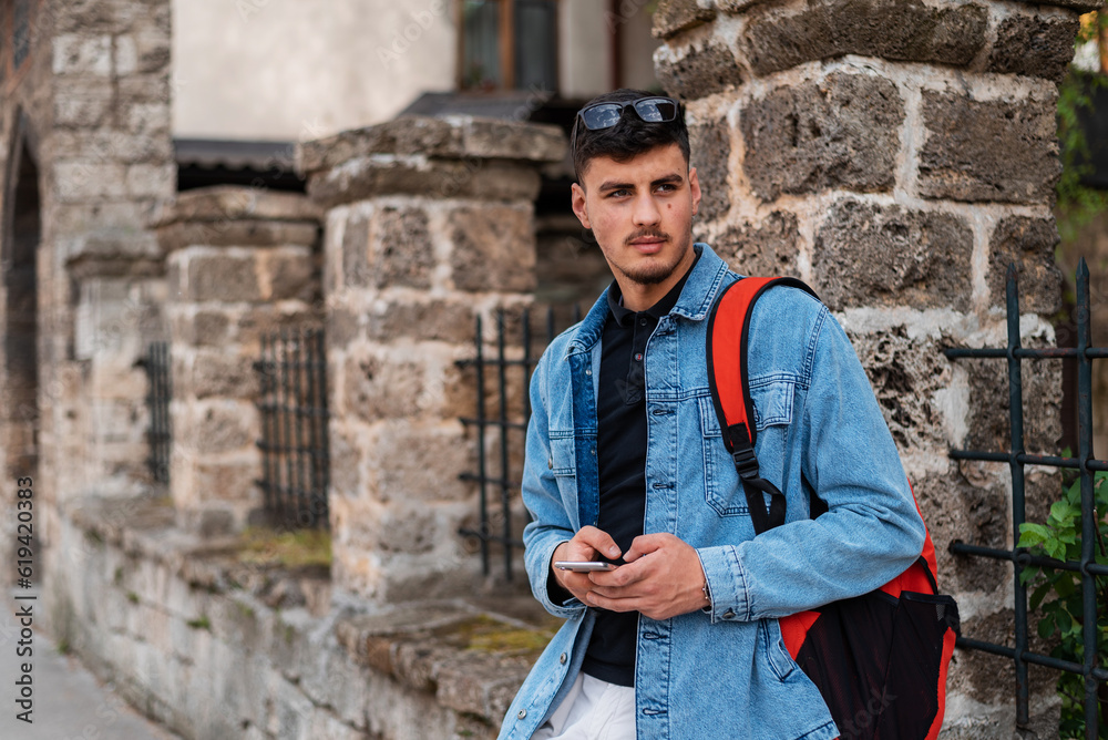 A young urban stylish man using a phone in the city street.