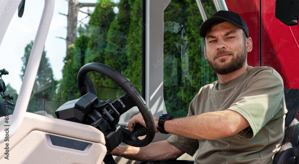 Portrait of worker sits in cabin of rotating telescopic handler machine looking at camera and smiling. Portrait of worker sits in cabin of rotating telescopic handler machine looking at camera and smiling.