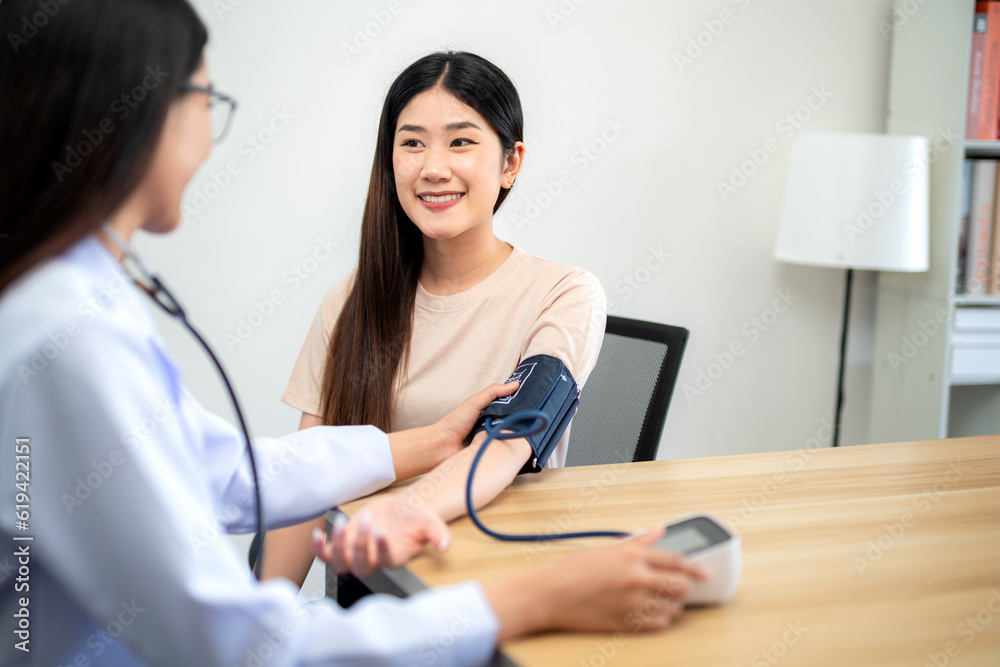 Asian female patient measuring blood pressure with digital sphygmomanometer with female doctor at hospital. Medical and health concept. Asian female patient measuring blood pressure with digital sphygmomanometer with female doctor at hospital. Medical and health concept.
