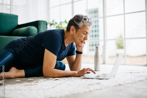 Mature woman searching for an online workout tutorial on her laptop photo