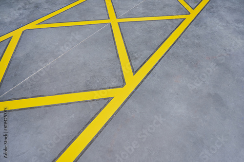 Yellow lines on the ground. Recently painted road marking on asphalt of a parking lot.