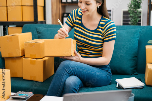 Shipping shopping online ,woman start up small business owner writing address on cardboard box at workplace.small business entrepreneur SME or freelance America woman working with box at home.