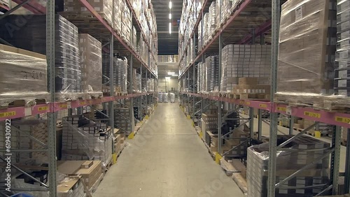 tilt up wide shot of ascending view of warehouse with very high ceilings and shelves full of goods