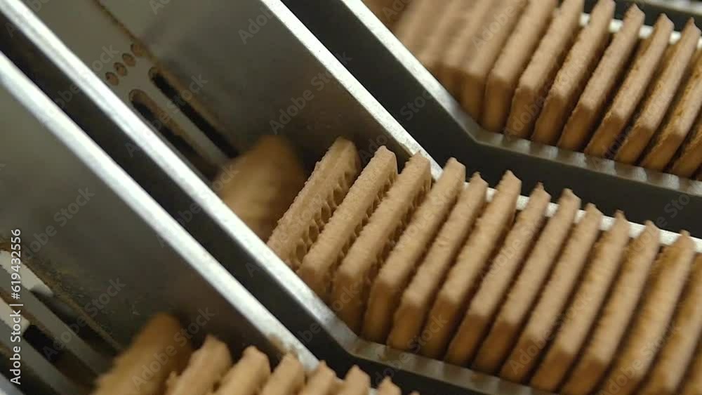 dolly slow motion macro shot of lots of square cookies being pressed together on a conveyor line before being packed