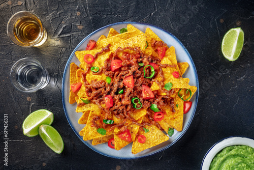 Nachos, Mexican food, tortilla chips with beef and fresh vegetables, overhead flat lay shot with tequila, guacamole, and limes, a party at a bar