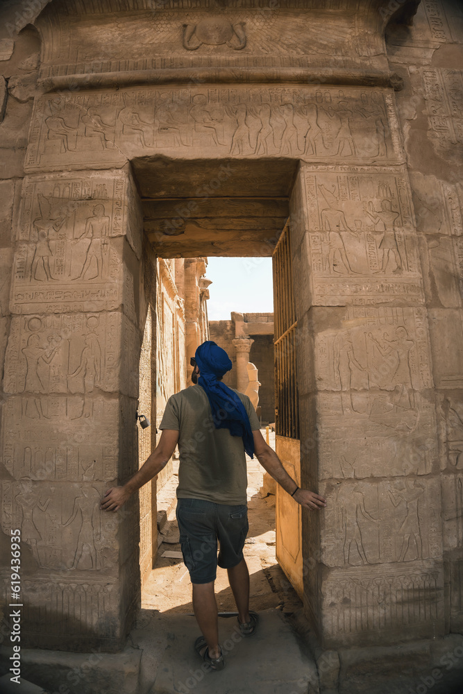 Portrait of a young man with a blue turban at the entrance to the Edfu Temple near the city of Aswan. Egypt, west bank of the nile in the city of Edfu, Greco-Roman construction, dedicated to Horus Portrait of a young man with a blue turban at the entrance to the Edfu Temple near the city of Aswan. Egypt, west bank of the nile in the city of Edfu, Greco-Roman construction, dedicated to Horus